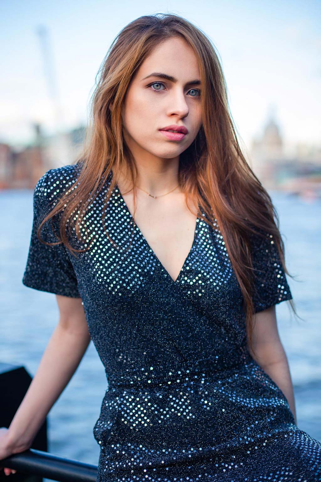 A pretty girl on a sequin dress against the river Thames in London, fashion photography by Nukemedia
